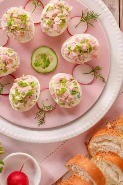 Deviled eggs, stuffed eggs filled with a paste made from smoked ham, mayonnaise, egg yolks and fresh chive on a plate, top view.Tasty breakfast, appetizer for party or holiday meals