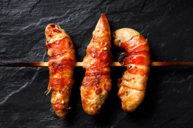 Siyah bir arka plan, üstten görünüm Pastırmalı Tavuk bonfile ızgara şiş sarılmış