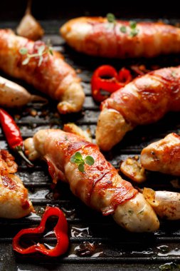 Baharat tavuk eti, ızgara tavuk bonfile yanı sıra biber, sarımsak ve ızgara tabakta otlar ile pastırma ile sarılmış yakın çekim 