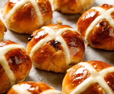 Hot cross buns, taze pişmiş sıcak cross buns beyaz parşömen kağıt üzerinde yakın çekim. Geleneksel Paskalya yemek
