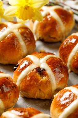 Hot cross buns, taze pişmiş sıcak cross buns beyaz parşömen kağıt üzerinde yakın çekim. Geleneksel Paskalya yemek