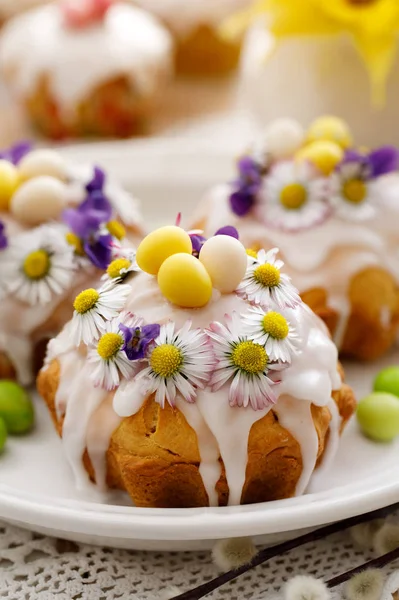 Easter cakes covered with icing decorated with spring and edible flowers on an Easter table. Easter delicious dessert