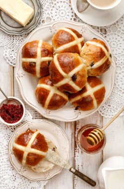 Hot cross buns, fırından yeni çıkmış sıcak cross buns bir beyaz plaka ve taze tereyağı, reçel ve bal ahşap bir masa üzerinde üstten görünüm yükseldi. Lezzetli breakfast, geleneksel Paskalya yemek