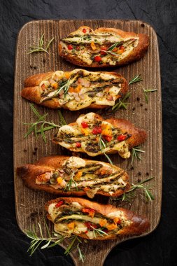 Izgara tost, eritilmiş peynir, yeşil kuşkonmaz, doğranmış domates, jambon, zeytinyağı ve otlar bir kesme tahtası, üst görünümü eklenmesi ile bruschetta.