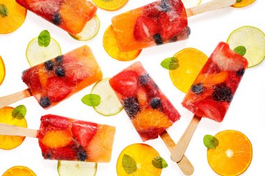Meyve Popsicles, çeşitli meyvelerin ev yapımı meyve buz Lolly; mandalinler, Limes, böğürtlen, yaban mersini, ahududu ve çilek beyaz arka planda limonata ilavesi ile, üst görünüm. 