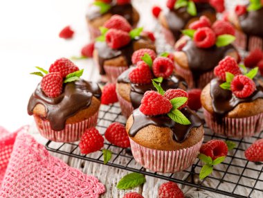 Bir soğutma tepsisinde eritilmiş koyu çikolata, taze ahududu ve nane ile Ahududu kekler, yakın. Lezzetli bir tatlı veya kahvaltı