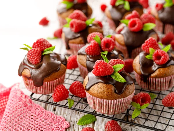 Bir soğutma tepsisinde eritilmiş koyu çikolata, taze ahududu ve nane ile Ahududu kekler, yakın. Lezzetli bir tatlı veya kahvaltı