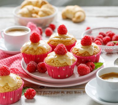 Beyaz çikolatalı kekler, taze ahududu ve tahta beyaz bir masada seramik bir tabakta naneli şekerler, yakın çekim. Lezzetli bir tatlı ya da kahvaltı.
