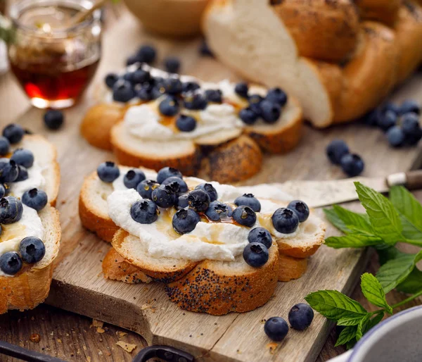 查拉面包片 在一块板上加入里科塔奶酪 新鲜蓝莓和蜂蜜 美味的素食 — 图库照片