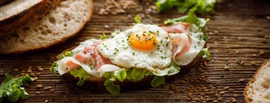 Jambon ve kızarmış yumurta açık sandviç, marul ile Sourdough ekmek sandviç, jambon ve rustik ahşap masada kızarmış yumurta, yakın çekim.