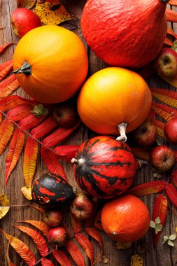 Taze olgun kabaklar ve ahşap bir masa üzerinde renkli sonbahar yaprakları, üst görünümü 