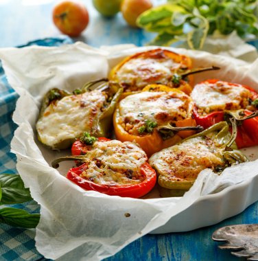 Biber dolması, bulgur la doldurulmuş biber yarım, kurutulmuş domates, otlar ve peynir bir fırın kabında, yakın çekim. Vejetaryen yemek, sebze dolması