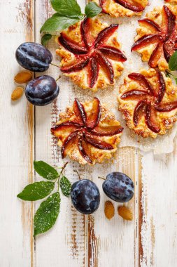 Küçük Erik tart, beyaz ahşap masada tarçın ile meyve hamur işleri, puf böreği ve tatlı erik ile lezzetli tatlı , üst görünümü, yakın çekim