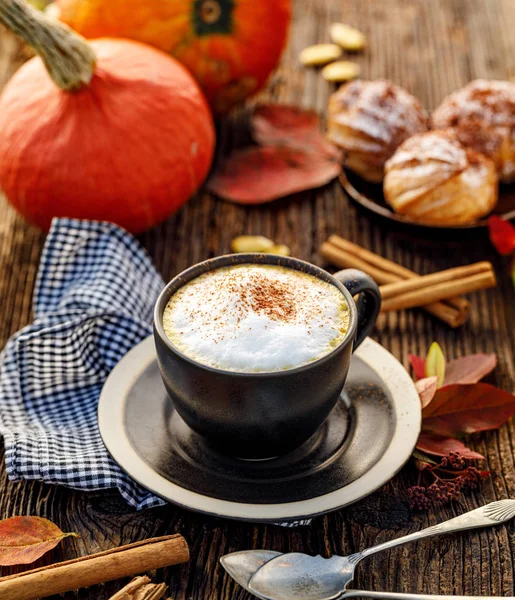 Pumpkin spice latte, coffee with the addition of pumpkin puree, aromatic spices,  sprinkled with cinnamon  in a cup on a wooden table, top view, close-up. Delicious and healthy hot drink