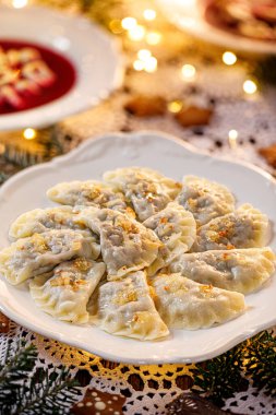 Christmas dumplings stuffed with mushroom and cabbage on a white plate on a holiday table, close-up. Traditional Christmas eve dish in Poland