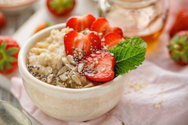Seramik kaseye taze çilek, tohum ve nane eklenmiş lapa. Sağlıklı kahvaltı.