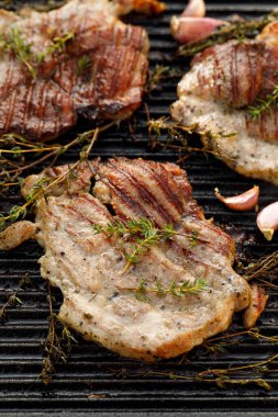 Izgara et, otlu domuz boynu ve dökme demir ızgara tabağında sarımsak, yakın görüş.