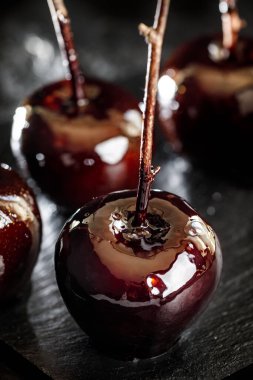 Cadılar Bayramı için siyah arka planda zehirli elma şekeri, tatlı partisi fikri yakın plan.