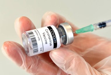 COVID-19 aşı şişesi, Pfizer laboratuarında elinde şişe. Beyaz arkaplanda yakın plan.