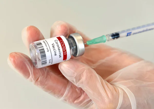 Coronavirus COVID-19 aşı şişesi, konteynır, eldivenli şişe. Beyaz arkaplanda yakın plan.