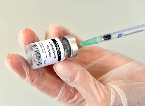 Coronavirus COVID-19 aşı şişesi, şişe, kap, eldiven Pfizer laboratuvarında. Beyaz arkaplanda yakın plan.