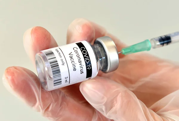 COVID-19 aşı şişesi, Pfizer laboratuarında elinde şişe. Beyaz arkaplanda yakın plan.