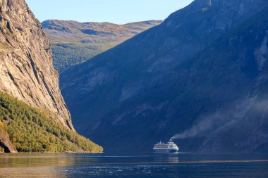 GEIRRANGER, NORway - 2017 Eylül 03. Norveç 'in en güzel Geiranger fiyordunda, fiyortta duman ve egzoz dumanı olan büyük bir yolcu gemisi..
