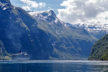 GEIRRANGER, NORway - 2016 Haziran 14. Fiyordun içinde seyir gemisi Geiranger 'den ayrılıp arka planda büyük dağların zirvesine ulaşır..