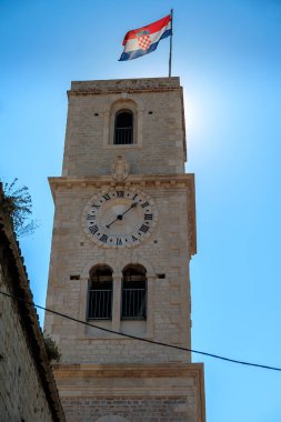 SIBENİK, CROATIA - 2017 AĞUSTOS 18. Hırvatistan bayraklı eski Sibenik kenti ve saatli kule çanı.