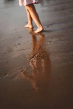 Çocuk plajda gün batımında koşar.