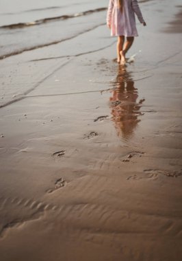Çocuk plajda gün batımında koşar.