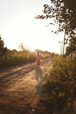 Mutlu bir çocuk gün batımında köyde yaz oyunu oynar.