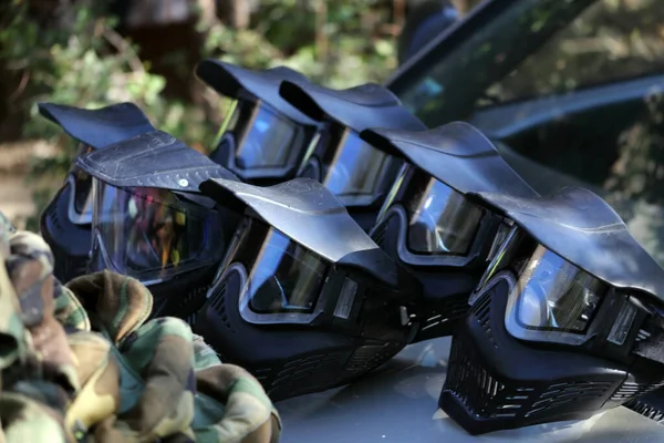 Açık havada güneşli bir günde arabanın kaputunda koruyucu paintball siyah maskeleri. Siyah koruyucu maske..