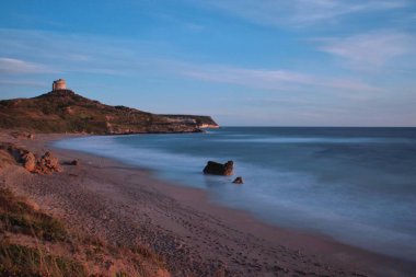 Arka planda İspanyol kulesi olan San Giovanni di Sinis plajının uzun metrajı. Fotoğraf Juin 12, 2020 'de çekildi. Konum: San Giovanni di Sinis, Sardinya, İtalya.