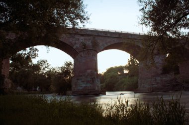 Tirso Nehri 'nin arka planda Roma köprüsü ve günbatımı ışıklarıyla uzun süre görünmesi. Fotoğraf 30 Temmuz 2020 'de çekildi. Konum: Afdongianus, Sardinya, İtalya.