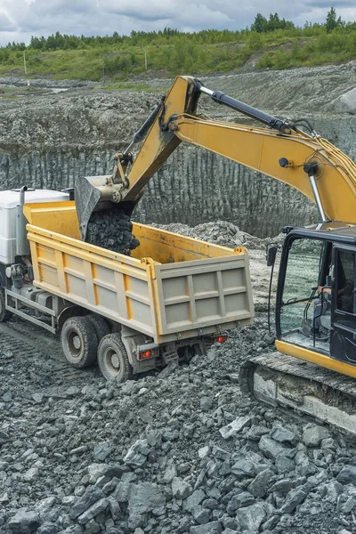 the process of loading the land with an excavator into the truck's hull on the construction site