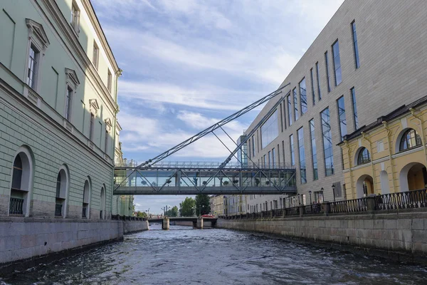 suspension bridge over a canal connecting  buildings against the background of an ancient bridge and blue sky
