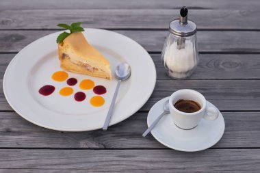  bir fincan kahve ve iştah açıcı cheesecake parça ahşap arka plan üzerinde bir tabakta reçel damlaları ile