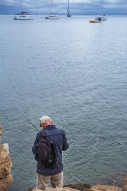 Balıkçı sahil üzerinde duruyor ve balık tutma malzemeleri hazırlar