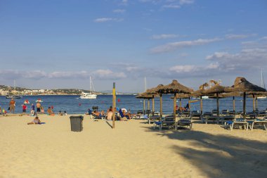 Güneşli kumlu plajda şemsiye ve şezlonglar ile mavi gökyüzü arka plan