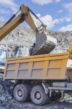 Bir kamyon ile mavi gökyüzü arka plan üzerinde bir ekskavatör yükleme işlemi