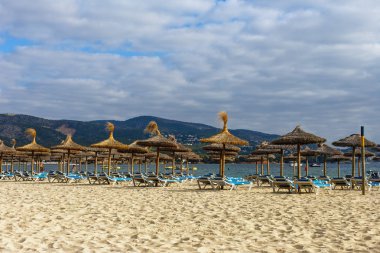 şezlong ve şemsiyeler mavi bir deniz ve bulutlu bir gökyüzü karşı kumlu bir plaj üzerinde