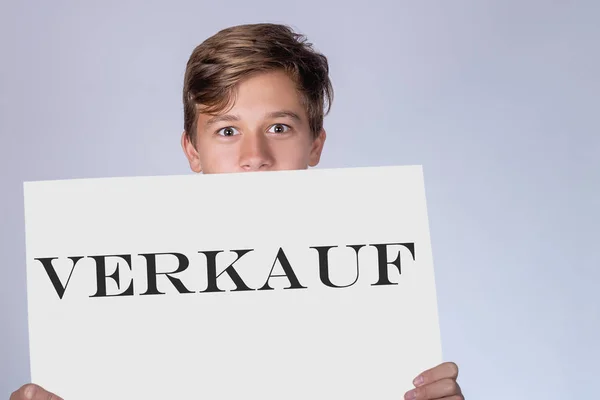 ドイツ語 Verkauf の銘刻文字と紙のシートと若い男 — ストック写真