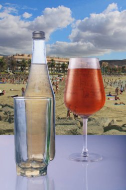 a bottle of refreshing lemonade and a glass of juice on the background of a hot summer beach on the Spanish island of Tenerife clipart