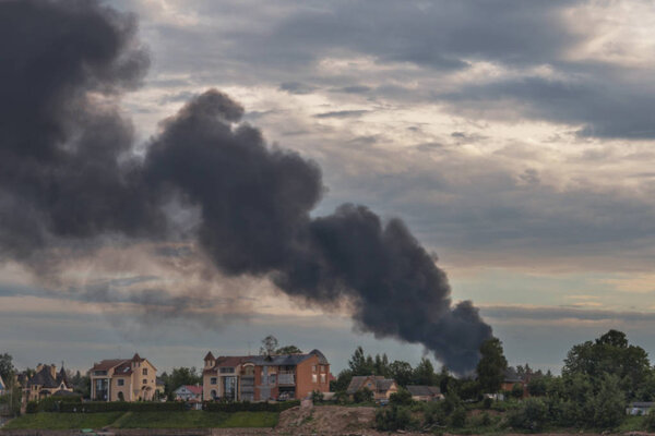 a dangerous cloud of black smoke from a burning house against the background of the evening sky as a background