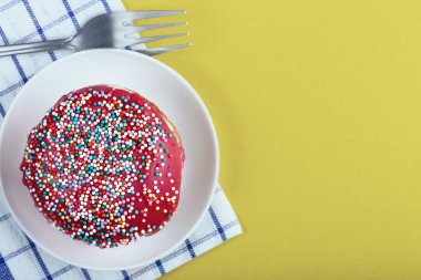 Renkli bir arka planda beyaz bir fincan tabağında renkli soslu taze, lezzetli bir çörek.