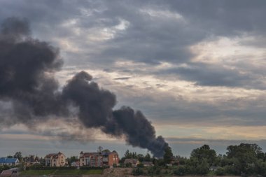 Yanan bir evden gelen tehlikeli bir kara duman bulutu akşam gökyüzünün arka planına karşı bir arka plan olarak