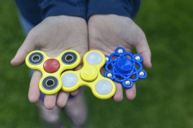 yeşil çim bulanık bir arka plan üzerinde bir çocuğun elinde üç çok renkli spinners
