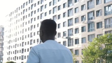 Ciddi bir Afro-Amerikan iş adamının kentsel şehirde keyfine bakması yakışıklı, kendine güveni tam, kendine güveni tam, sokakta yürüyor.