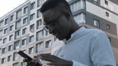 Akıllı telefon kullanan yakışıklı Afro-Amerikan iş adamı. Mutlu neşeli genç zenci dans ederken mesajlar, mutlu erkek yüzü, gerçek duygular